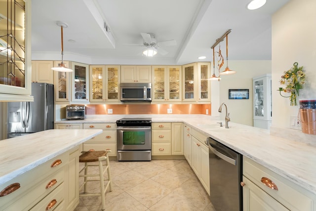 kitchen with stainless steel appliances, sink, cream cabinetry, and decorative light fixtures