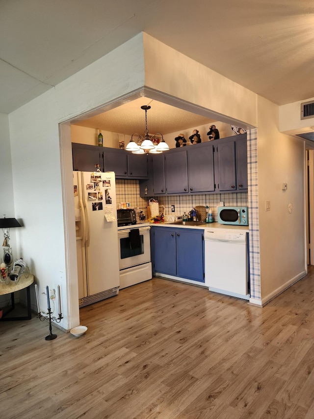 kitchen with white appliances, tasteful backsplash, light wood-style flooring, and light countertops