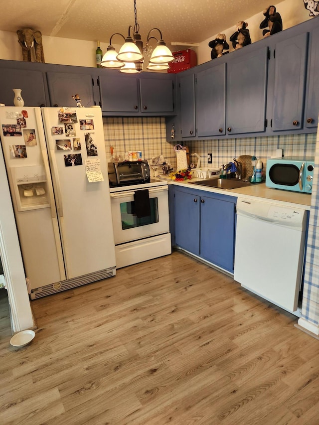 kitchen featuring white appliances, backsplash, a sink, and light wood-style floors