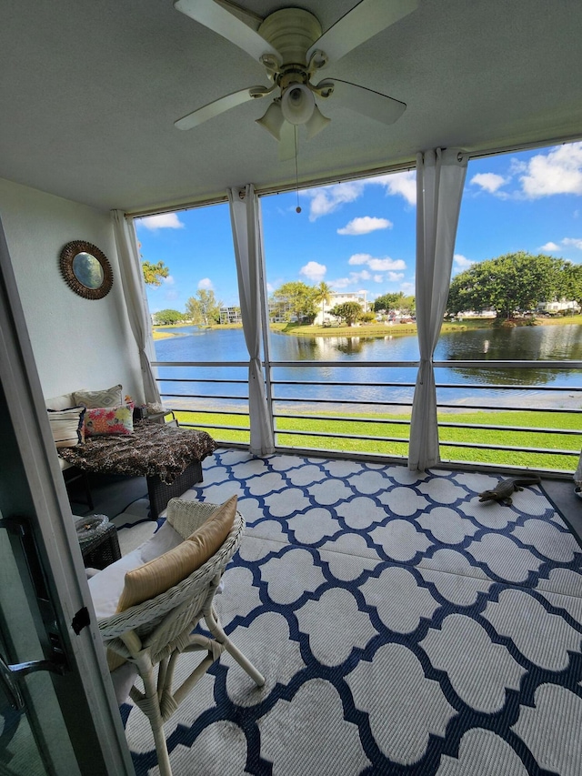 sunroom featuring plenty of natural light, a water view, and a ceiling fan