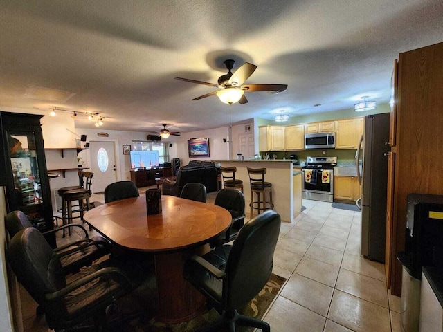 tiled dining space with ceiling fan and a textured ceiling