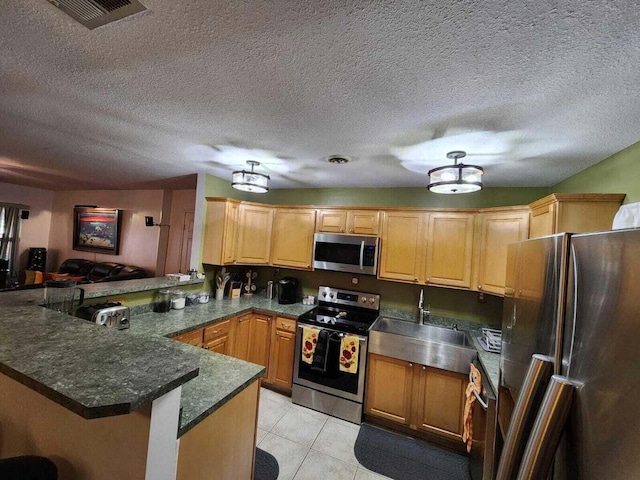 kitchen featuring appliances with stainless steel finishes, sink, light tile patterned floors, kitchen peninsula, and a textured ceiling