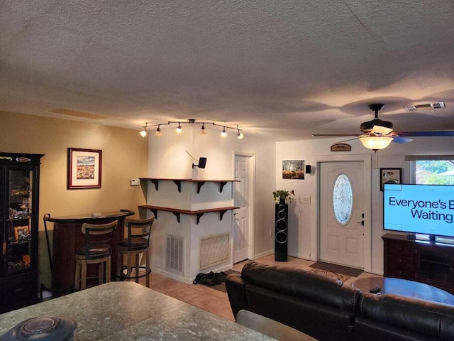 living room featuring ceiling fan, light tile patterned floors, bar area, and a textured ceiling