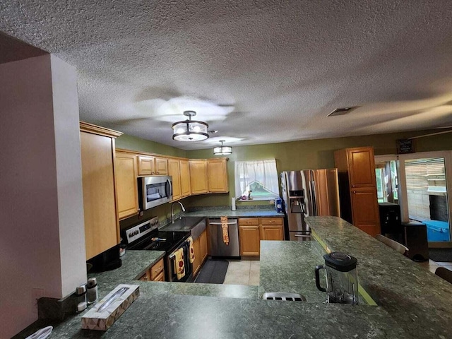 kitchen featuring sink, kitchen peninsula, a textured ceiling, and appliances with stainless steel finishes