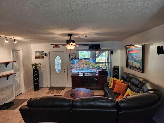 living room featuring light tile patterned flooring, ceiling fan, and a textured ceiling