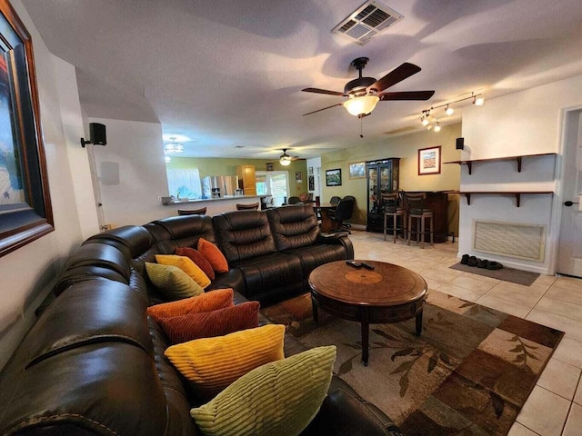 living room with ceiling fan, a textured ceiling, and light tile patterned floors