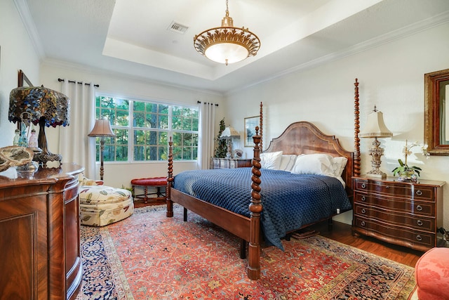 bedroom with dark wood-type flooring, ornamental molding, and a tray ceiling