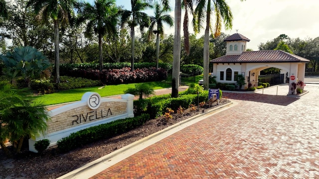 community / neighborhood sign with curved driveway and a yard