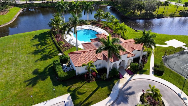 aerial view of property and surrounding area with a nearby body of water and a pool area