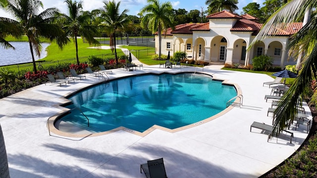 community pool with a patio area and fence