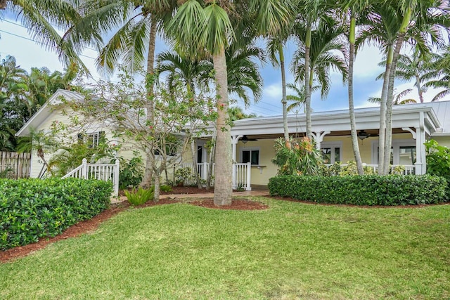 rear view of property featuring ceiling fan and a lawn