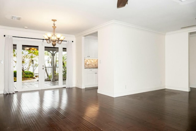 empty room featuring crown molding, dark wood-type flooring, and a chandelier