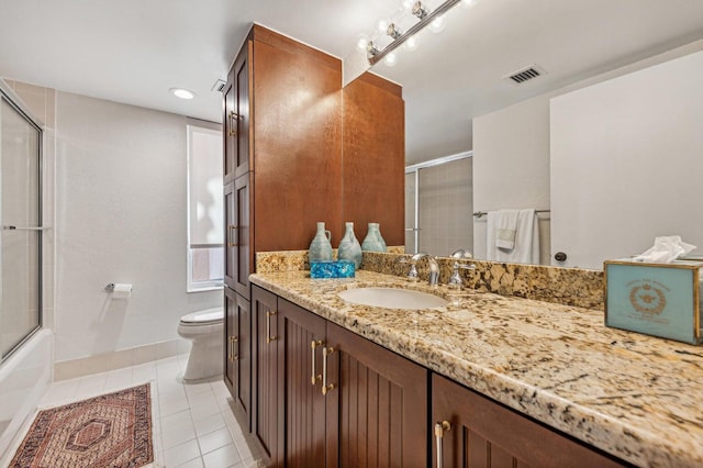 full bathroom featuring vanity, bath / shower combo with glass door, tile patterned floors, and toilet