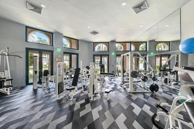 gym featuring dark carpet, french doors, and a towering ceiling