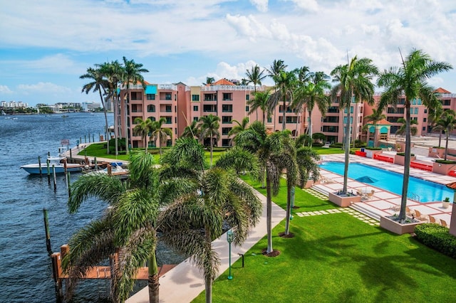 view of swimming pool with a patio, a water view, a boat dock, and a lawn