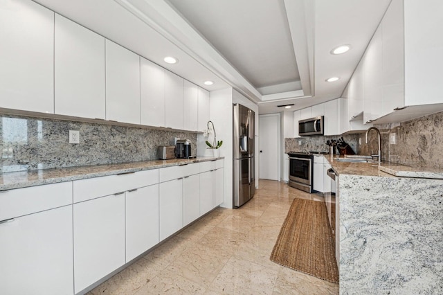 kitchen featuring sink, light stone counters, tasteful backsplash, appliances with stainless steel finishes, and white cabinets