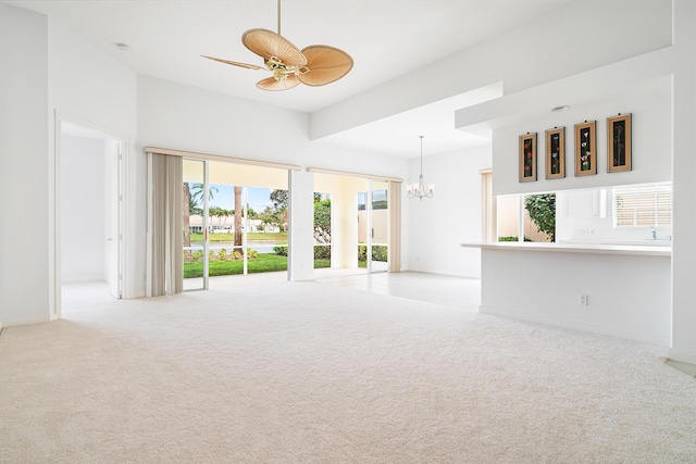 spare room featuring light carpet, baseboards, and ceiling fan with notable chandelier