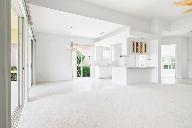 unfurnished living room featuring light tile patterned floors, plenty of natural light, an inviting chandelier, and light colored carpet