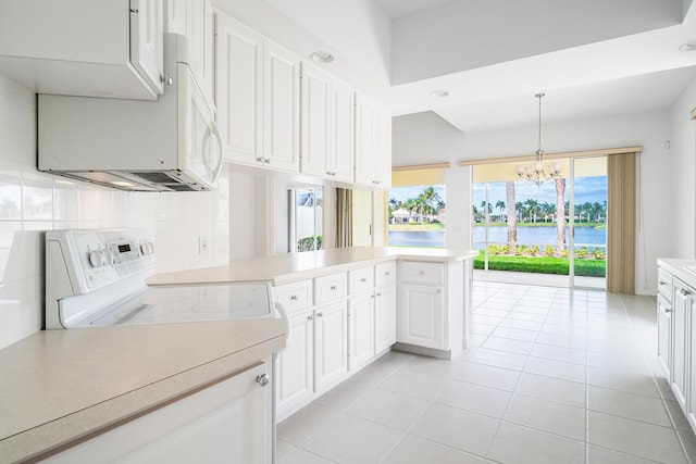 kitchen featuring a peninsula, a water view, light countertops, and hanging light fixtures