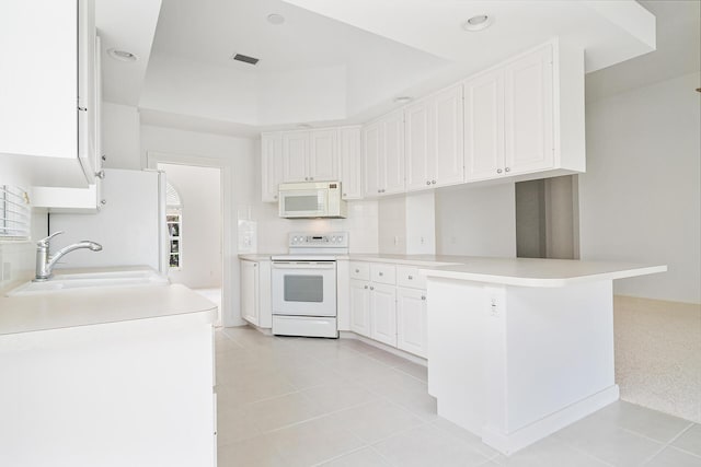 kitchen with a peninsula, white appliances, a sink, white cabinetry, and light countertops