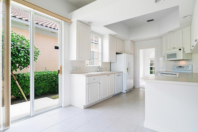 kitchen featuring white appliances, white cabinetry, light countertops, and a tray ceiling