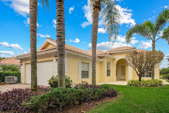 view of front of house with an attached garage, central AC, a tile roof, a yard, and stucco siding