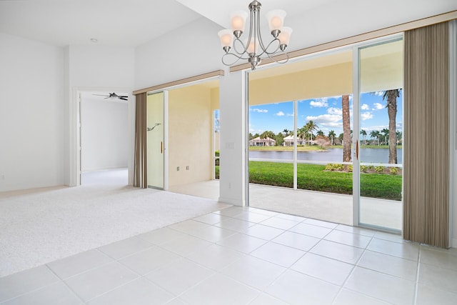 empty room featuring light colored carpet, a water view, light tile patterned flooring, and an inviting chandelier