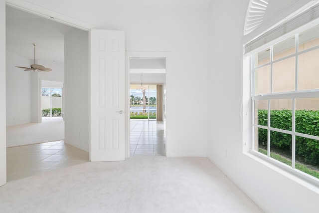 unfurnished room with light carpet, light tile patterned floors, and ceiling fan with notable chandelier