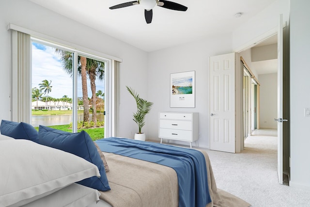 bedroom featuring baseboards, light colored carpet, ceiling fan, a water view, and access to exterior