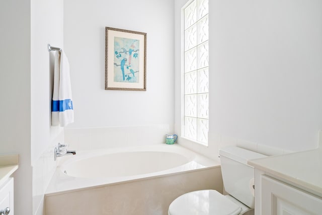 bathroom featuring toilet, a garden tub, and vanity