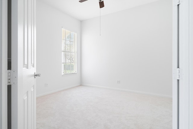 unfurnished room featuring light carpet, a ceiling fan, and baseboards