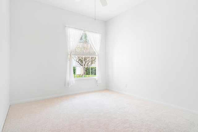 empty room featuring baseboards, a ceiling fan, and light colored carpet