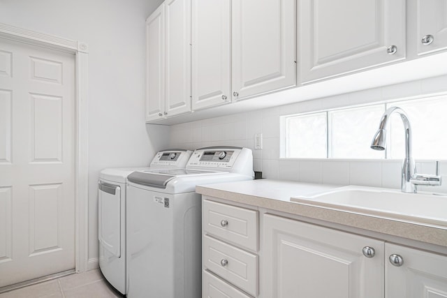 washroom featuring cabinet space, light tile patterned floors, separate washer and dryer, and a sink