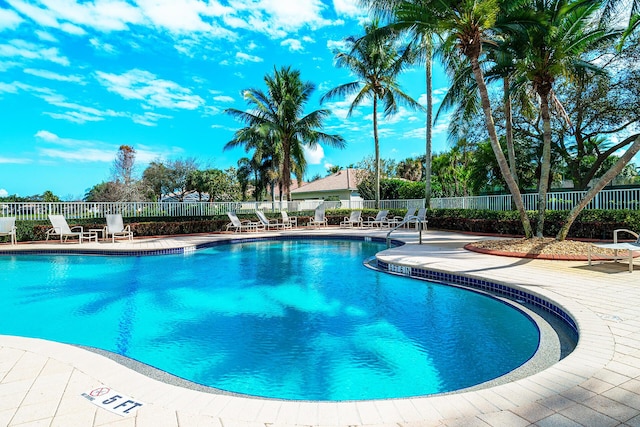 community pool with a patio area and fence