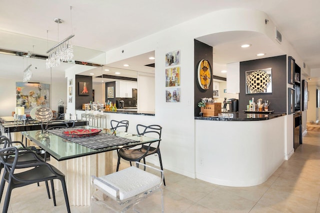 kitchen featuring pendant lighting, white cabinetry, tasteful backsplash, light tile patterned flooring, and kitchen peninsula