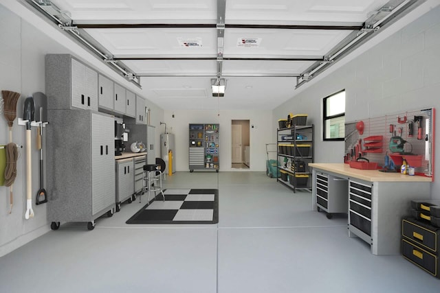 garage with a garage door opener, electric water heater, and a workshop area