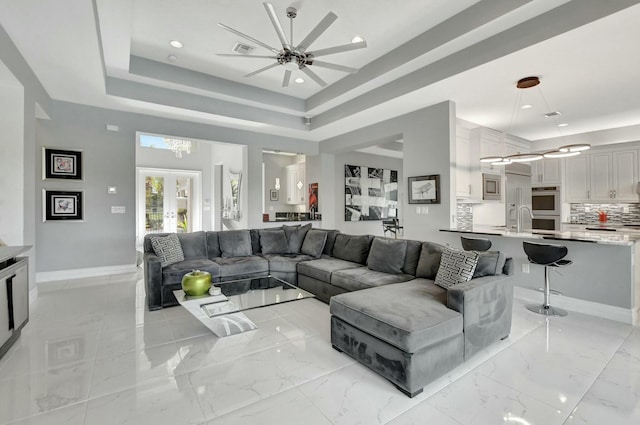 living room with french doors, sink, ceiling fan, and a tray ceiling