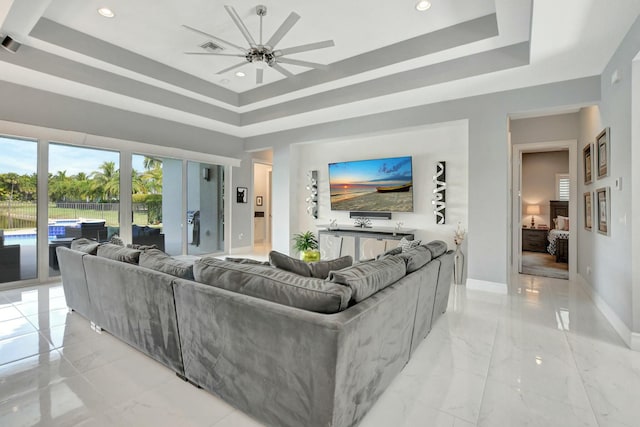 living room with ceiling fan and a raised ceiling