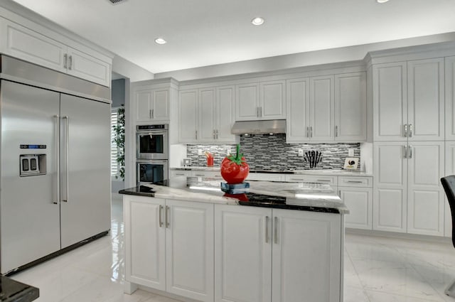 kitchen featuring tasteful backsplash, light stone counters, stainless steel appliances, and white cabinetry