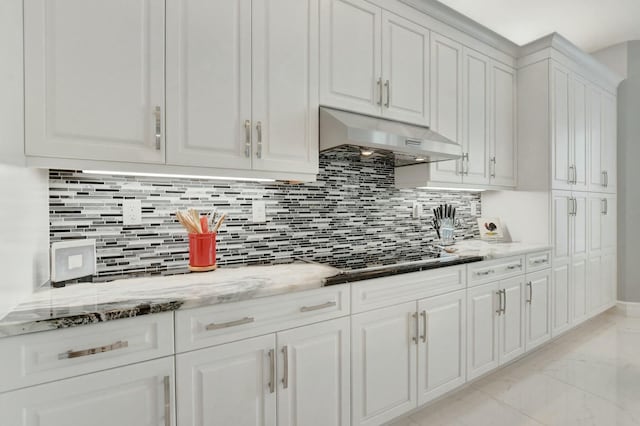 kitchen featuring dark stone countertops, tasteful backsplash, gas stovetop, white cabinets, and exhaust hood