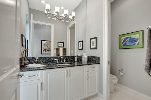 bathroom featuring vanity, toilet, and a notable chandelier