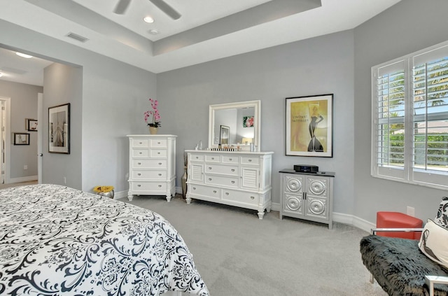 bedroom with a tray ceiling, light colored carpet, and ceiling fan