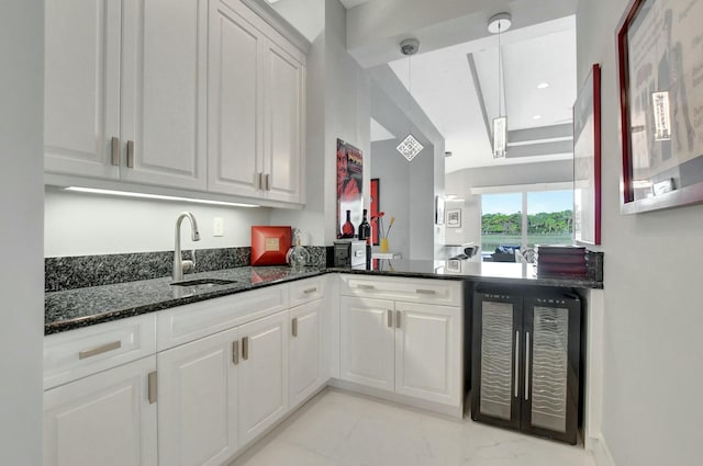 kitchen with hanging light fixtures, white cabinetry, sink, and wine cooler