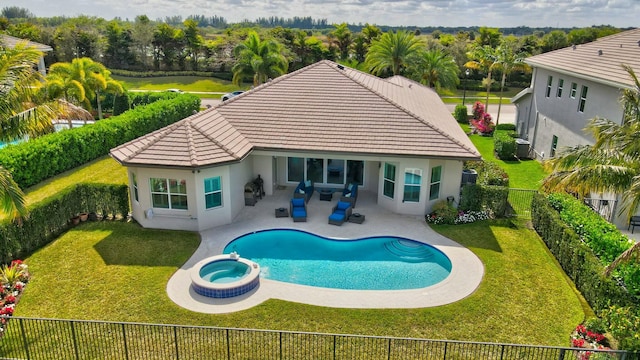 back of property with a swimming pool with hot tub, a yard, and a patio