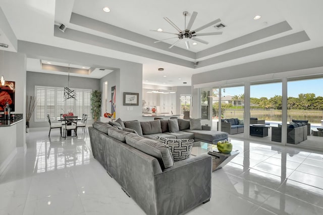 living room featuring ceiling fan, a raised ceiling, and a wealth of natural light