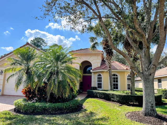 mediterranean / spanish home featuring a garage and a front lawn