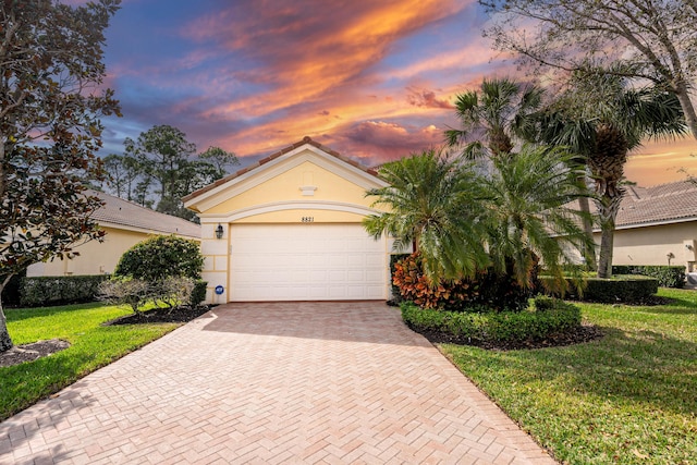 view of front of house featuring a lawn, decorative driveway, and stucco siding