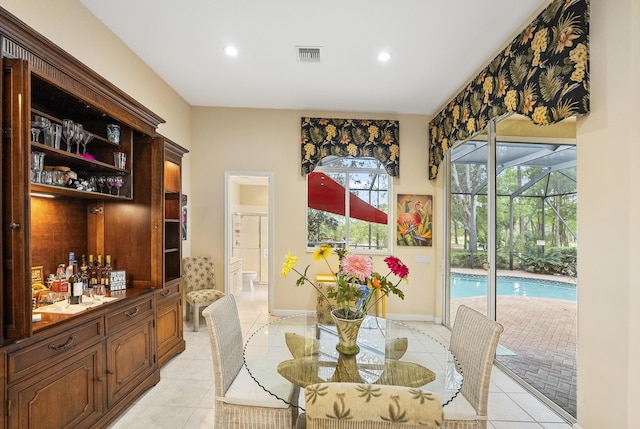 dining space with baseboards, visible vents, light tile patterned flooring, a sunroom, and a dry bar