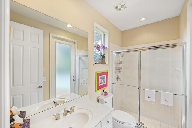 bathroom with vanity, toilet, visible vents, and a stall shower