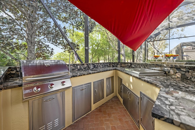 view of patio / terrace with glass enclosure, area for grilling, and a grill